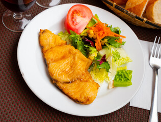 Popular Andalusian dogfish ration. Fried dogfish with sliced vegetables served on white plate, Spanish dish