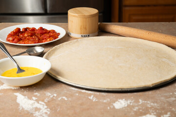 Pizza Crust with eggs and tomatoes on counter