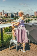 Woman with silver hair stands in front of a city view on a building rooftop