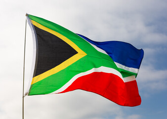Large flag of South Africa waving against sky and clouds..