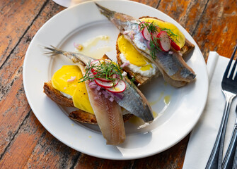 Dutch soused herring served on pieces of bread with radish and yoghurt.