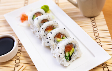 Sake roll with salmon, avocado and served with bowl of soy sauce