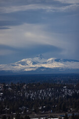 Snowy mountain with rays of sunlight shining through dark clouds