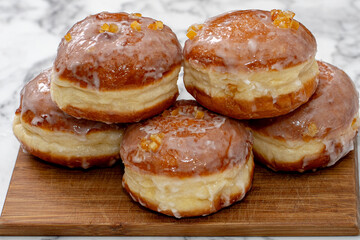 Freshly baked Polish doughnuts (paczki) with a golden-brown crust, glazed with icing and sprinkled with powdered sugar and candied orange peel. A traditional Fat Thursday treat full of flavor.
