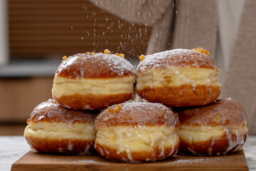 Freshly baked Polish doughnuts (paczki) with a golden-brown crust, glazed with icing and sprinkled with powdered sugar and candied orange peel. A traditional Fat Thursday treat full of flavor.