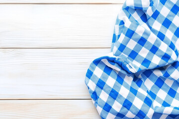Obraz premium Blue and White Checkered Tablecloth on Wooden Surface with Rustic Charm and Textural Appeal