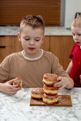 Two young boys eagerly admire a stack of traditional Polish paczki, glazed and filled with custard,...
