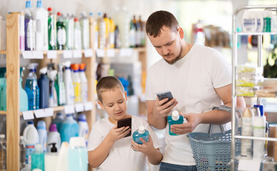 Dad and son scan barcode on packaging of mouthwash, looking for information about product on...