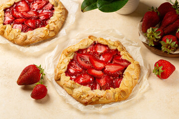 Two Strawberry Galette with almonds.  Homemade  open pie or tart with berries on a beige table.