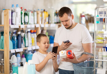 Young man with his son buyers scanning qr code for unclogging gel in household chemicals store