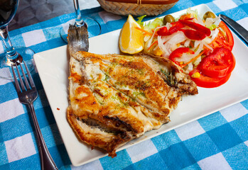 Fried cut dorada fish dressed with spicy fragrant pesto served on white plate with vegetable...