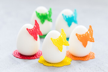 Holiday Easter. Mousse dessert in the shape of an Easter egg. Decorated with colorful waffle lace decor in the shape of butterflies. Close up