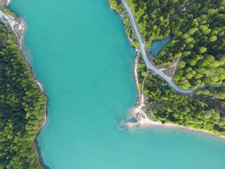 car drives along a road along a mountain lake, forest and sandy cape,aerial view