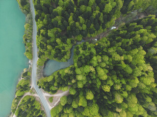 car drives along a road along a mountain lake, forest and sandy cape,aerial view