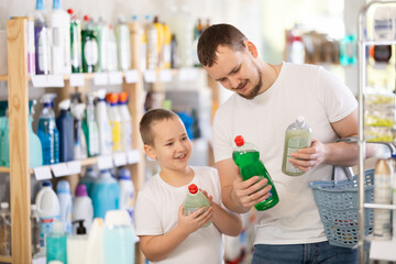 Boy and father in process of choosing dishwashing, looking at packages, reading labels on packages....