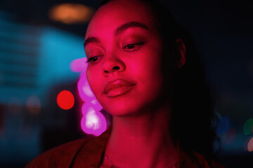 Close-up portrait of young woman bathed in neon pink light,captivating gaze reflect confidence and...