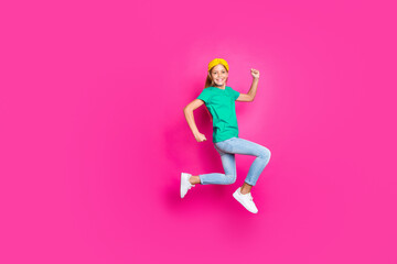 Full size photo of positive cheerful kid jump run have fun enjoy spring holiday discounts wear blue denim jeans clothes sneakers isolated over pink color background