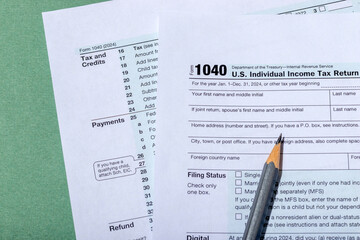 Close-up USA individual income tax return form 1040 on green background. Tax time concept