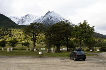 A passenger car parked in a camping area near large mountains