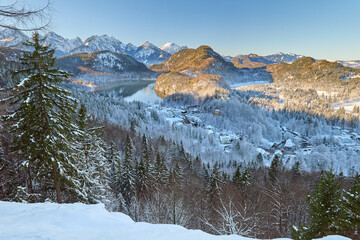 View of snowy mountain landscape with lake and mountains near Neuschwanstein Castle, capturing early morning light in beautiful winter area, showcasing detailed high-quality photograph of icy