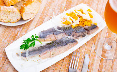 Sliced herring with corn and herbs on rectangular plate in cafe. Healthy food