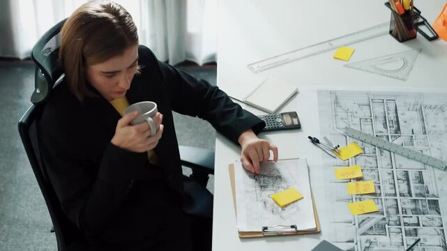 Top view of architect engineer drink coffee and draw blueprint at meeting table with equipment and safety helmet scatter around. Aerial view of project manager looking at project plan. Alimentation.