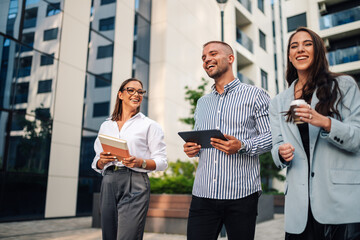 Business people walking outside office building and smiling