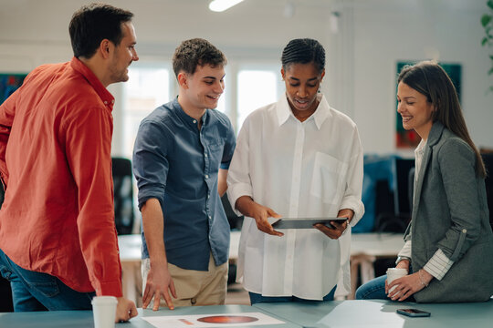 Marketing team analyzing data on tablet and printed documents during a meeting