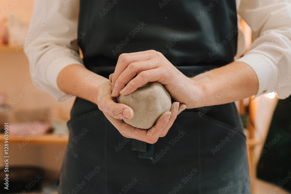 Poster Girl potter is creating a ceramic ware in the workshop. Woman potter works with wet clay in the pottery studio.