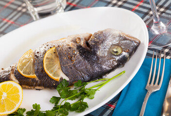 Baked in oven dorado fish with orange served with parsley on plate