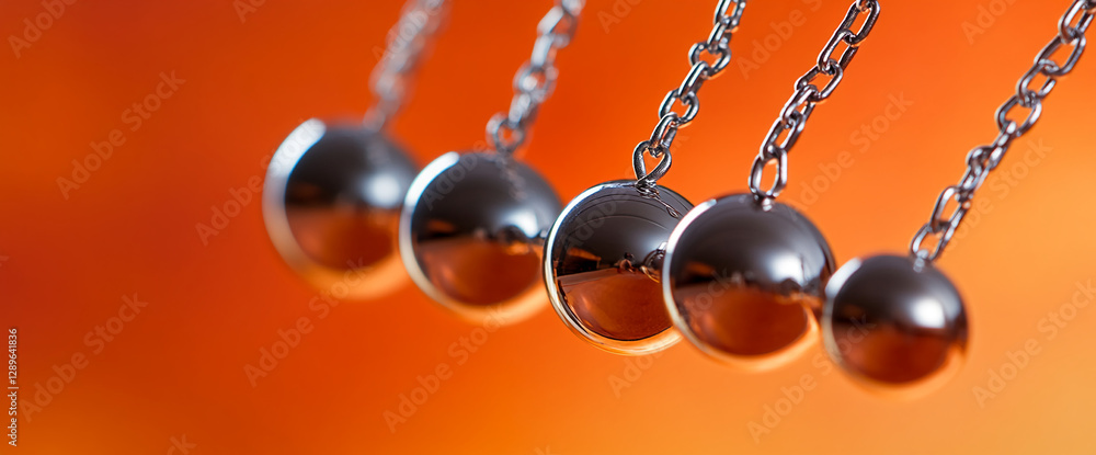 Poster five metallic spheres on chains suspended against an orange gradient background, symbolizing balance