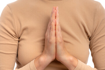 A close-up of hands pressed together in a prayer position against a white background.