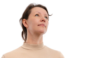 A woman in a beige turtleneck sweater gazing upward against a white background.
