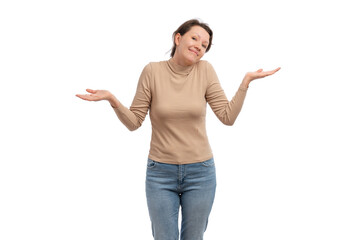 A young woman in a beige top smiling and shrugging her shoulders against a white background.