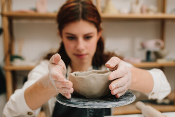 Female potter hands shows ceramic bowl ready for firing in a kiln. The process of creating ceramic...