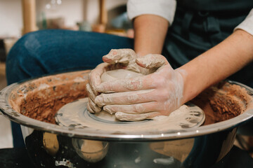 Process of making ceramic earthenware on the spinning wheel in the pottery studio. Artisan molds a...