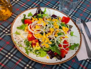 Appetizing salad with corn, arugula and tomatoes on a plate