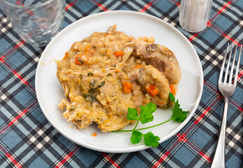 Thick white navy bean stew with hare meat, onion and carrot