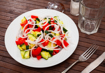 Vegetarian salad with tomatoes, cucumbers and onion with olive oil at plate