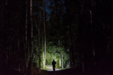 Man standing outdoor at rainy foggy night shining with flashlight. Mystical and abstract photo of...