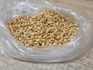 The kernels of peeled pine nuts in a transparent plastic bag for sale by weight on the market....