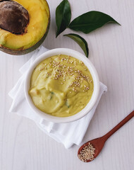 bowl with avocado cream, guacamoe and seasonings on light background