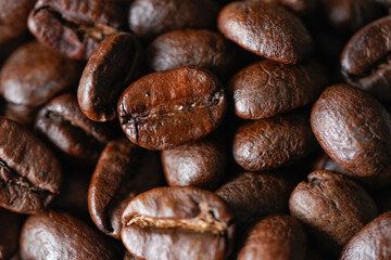 Striking close-up of vibrant, dark roasted coffee beans, highlighting their glossy texture and rich, earthy tones. This high-quality stock photo captures the essence of freshly roasted coffee.