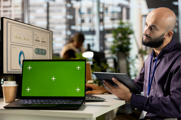 Professional analyst engages in project management next to chroma key display, working on global expansion for the company. Male employee focusing on strategy planning to drive corporate success.