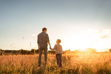 Happy father and son parent and child holding hands  walking together in nature park