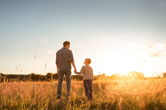 Happy father and son parent and child holding hands  walking together in nature park