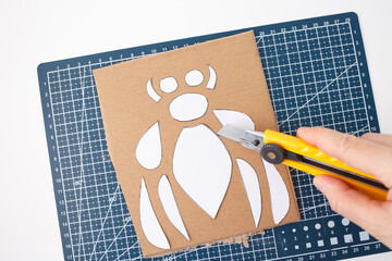colorful cutting mat with a grid design, various craft tools like utility knife, and neatly cut...