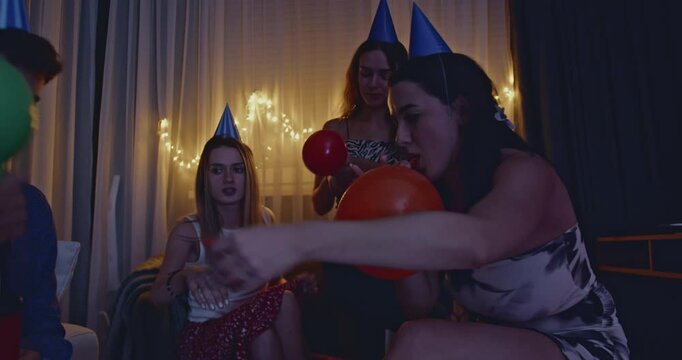 Friends blowing up balloons and having fun at a birthday party. Joyful, happy, and festive atmosphere with colorful balloons and party hats.