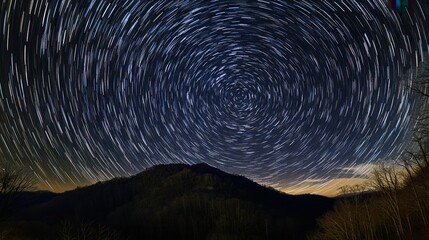 Fototapeta premium Star Trails Above Mountain Landscape Captured in Long Exposure Photography at Night Sky with Beautiful Celestial Patterns
