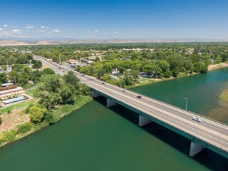 Highway bridge spanning Sacramento River showcasing a town nestled beside the water. Traffic flows...